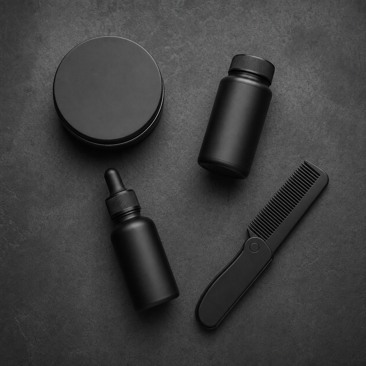 Matte black pomade tin, texture powder, beard oil and a folding comb on a dark surface